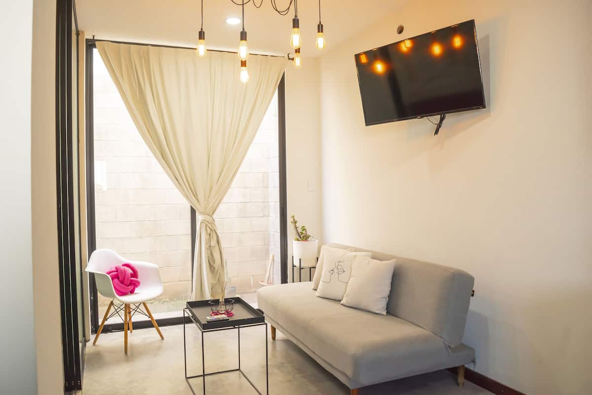 A modern living room with a sofa, a chair, a coffee table, and a TV mounted on the wall.