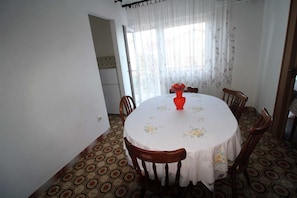 Un coin repas avec une table ronde, des chaises, un vase de fleurs et un sol à motifs.