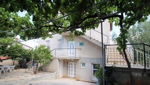 A residential building with a stone patio, a balcony, and a staircase leading to an upper floor. - Charming 2-Bedroom Haven for Four, No Pets (Pula)