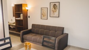 Una sala de estar moderna con un sofá, una mesa con una vela, un mueble de madera y un lavamanos empotrado en la pared.
