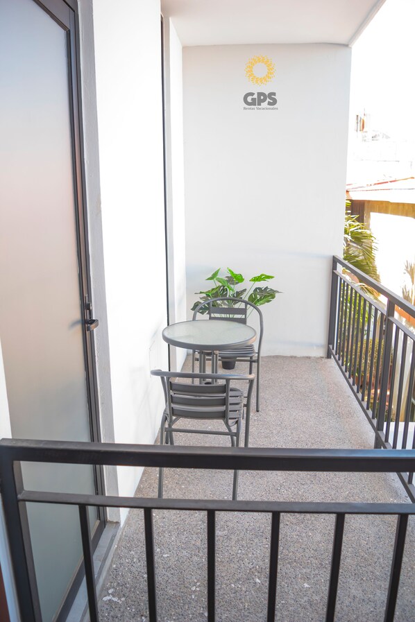 A balcony with a table and chairs, a small potted plant, and a sign with the logo "GPS".