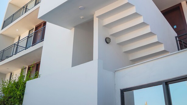 Un edificio moderno de varios pisos con balcones, una escalera y cielo despejado.