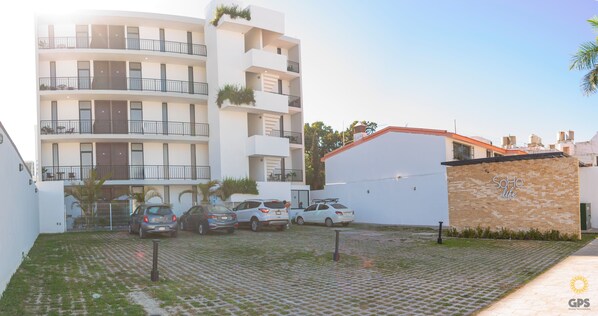 Un edificio residencial de varios pisos con un estacionamiento al frente.