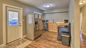Cocina compacta con refrigerador, microondas, lavavajillas y basurero.