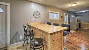 Una cocina con una isla de madera, taburetes de bar, un refrigerador y un ventanal.