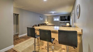Una cocina con isla de madera, taburetes de bar y una mesa de comedor.