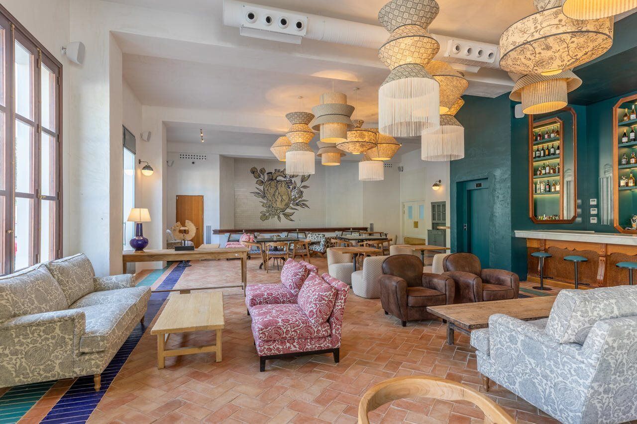 A spacious lobby with multiple seating areas, a bar with shelves of bottles, and a large abstract artwork on the wall.