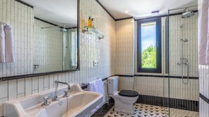 Une salle de bain moderne dotée d’un grand lavabo, de toilettes et d’une douche. Elle comprend un grand miroir, une fenêtre et un sol carrelé.