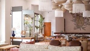 Un salón espacioso con un sofá grande, varias sillas, una mesa de comedor y un espejo grande.