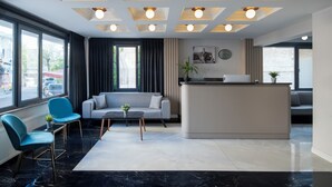 Un moderno vestíbulo de hotel con mostrador de recepción, zona de estar y grandes ventanales.