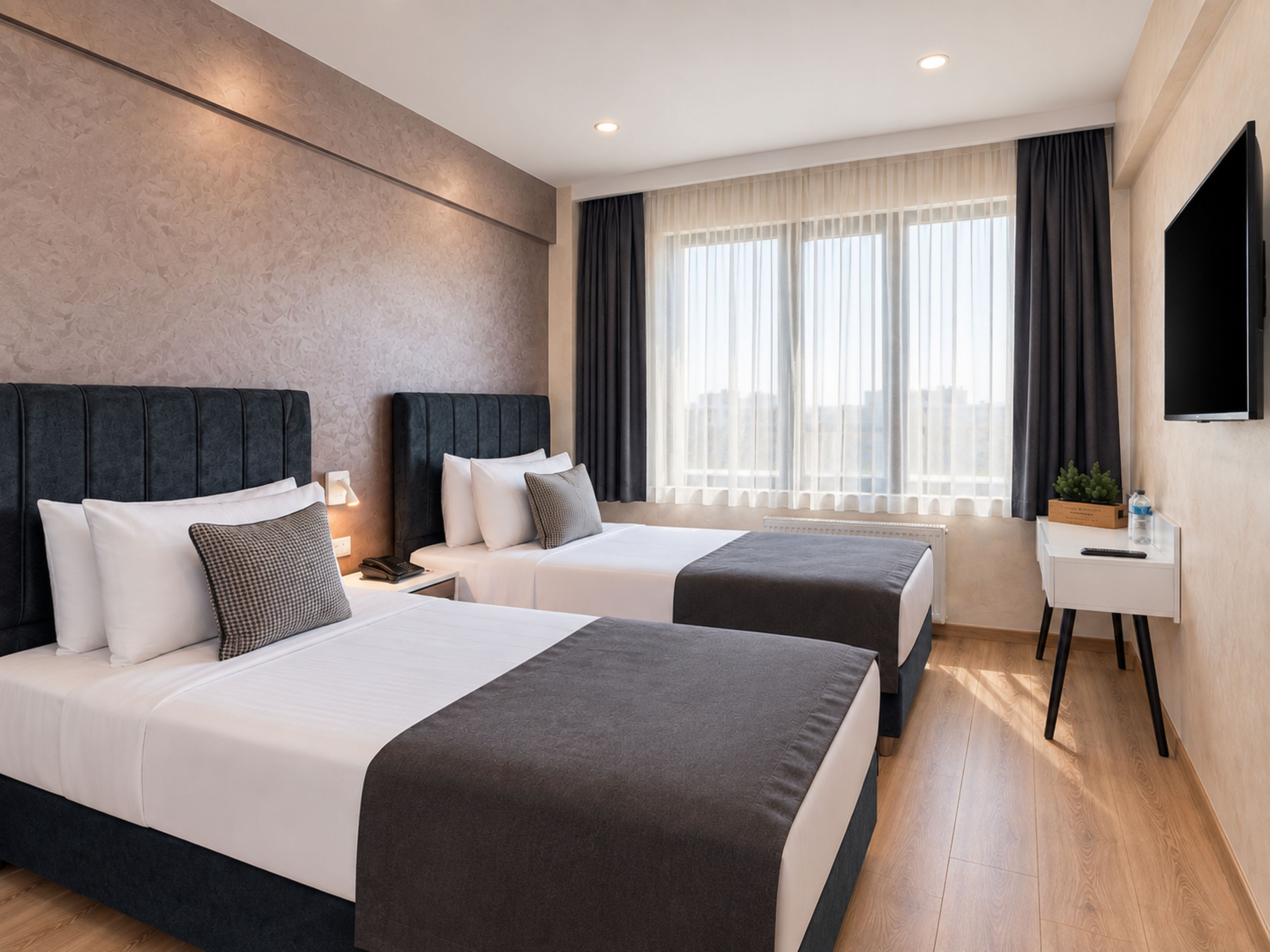 A hotel room with two beds, a flat-screen TV, a bedside table with a remote, and a window with curtains.