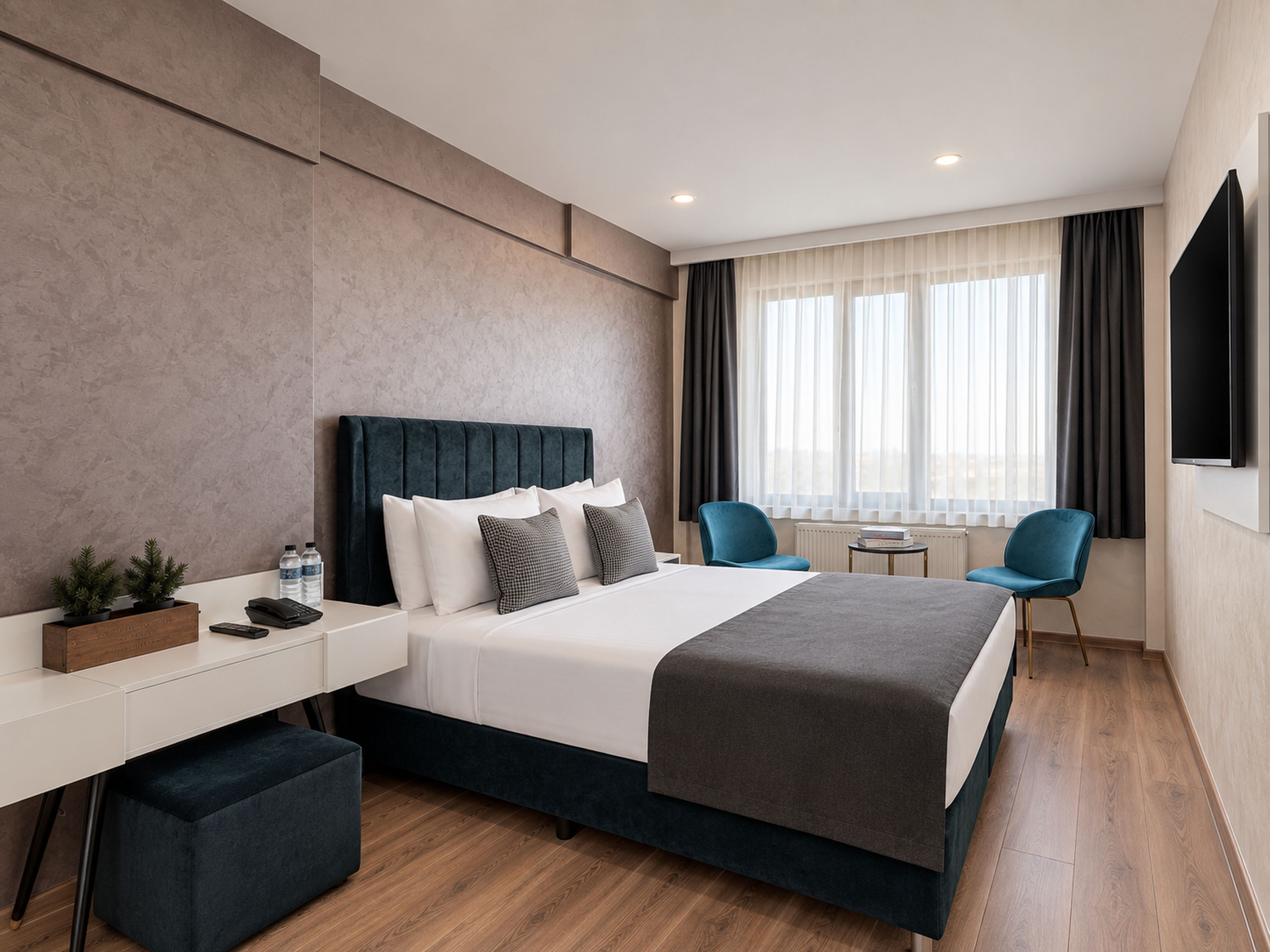 A modern hotel room with a bed, bedside tables, a desk, a chair, and a TV.