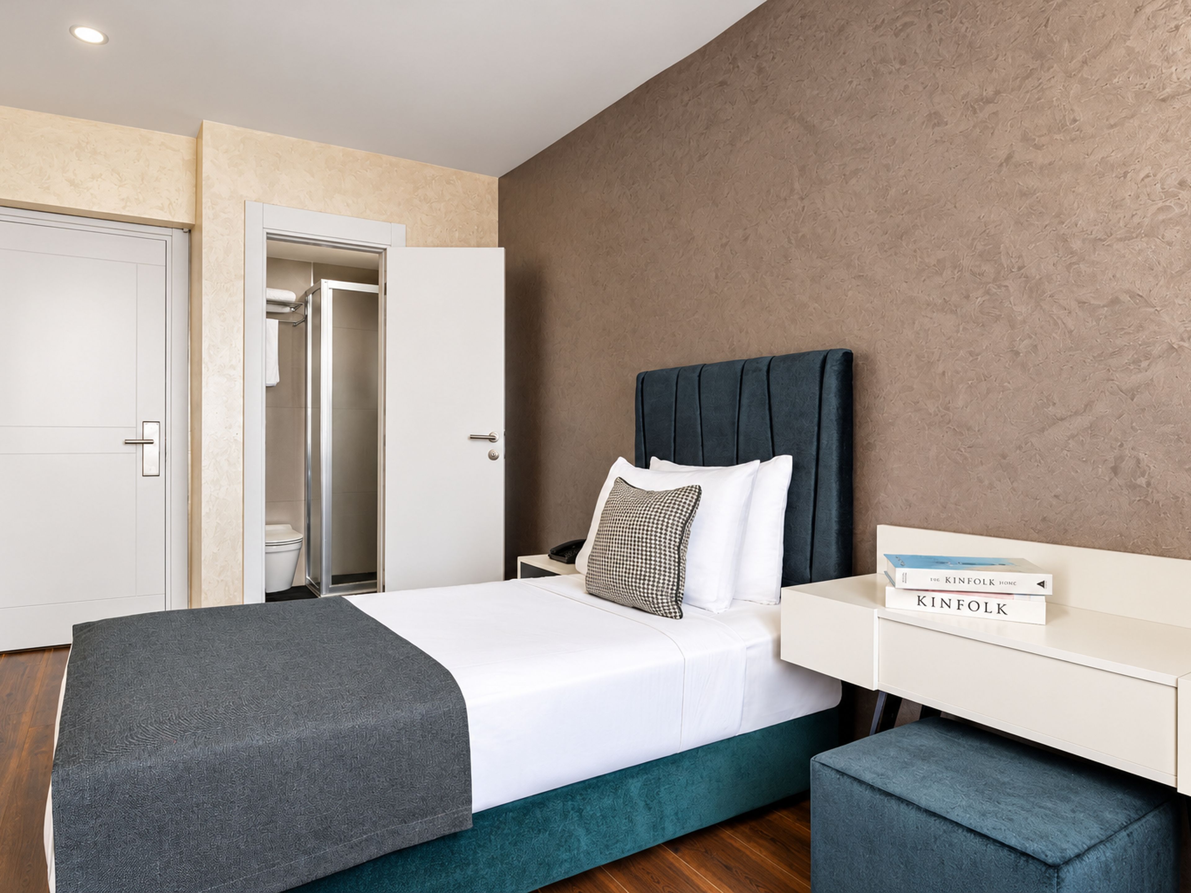 A modern bedroom with a bed, bedside table, and a book titled 'The Kinfolk Home'.