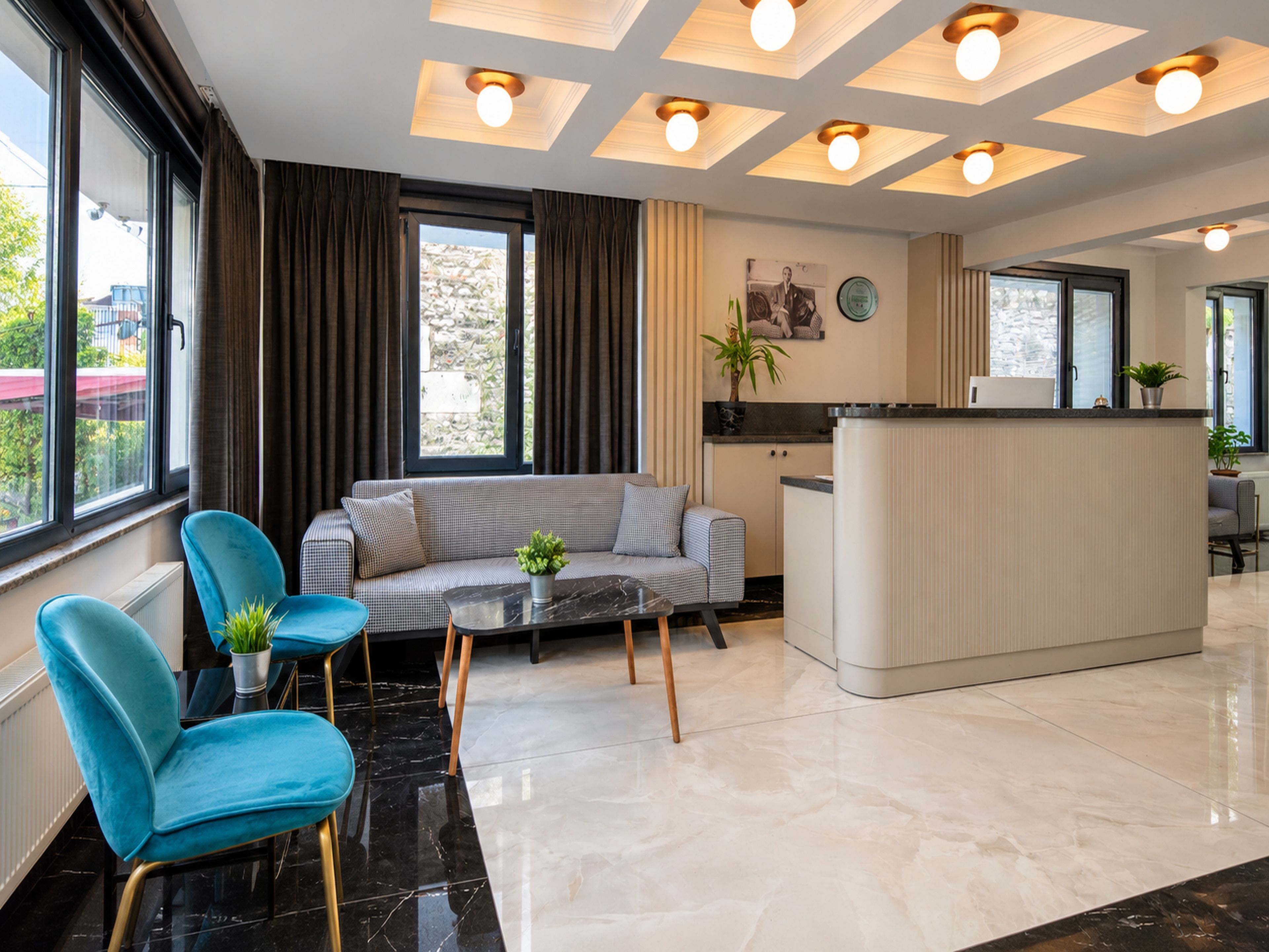 A modern hotel room with a sofa, chairs, a small table, and a kitchen area.