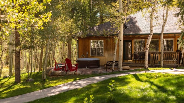 Une cabane avec une véranda, un jacuzzi et un fauteuil rouge.