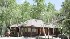 Un chalet avec une façade en bois, de grandes fenêtres et une véranda.