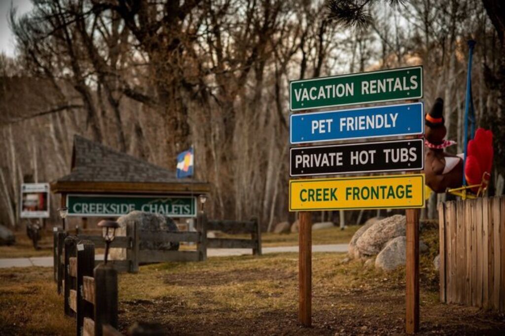 Une enseigne indiquant : « Locations de vacances », « Animaux acceptés », « Baignoires à remous privées » et « Bord d’un ruisseau ».
