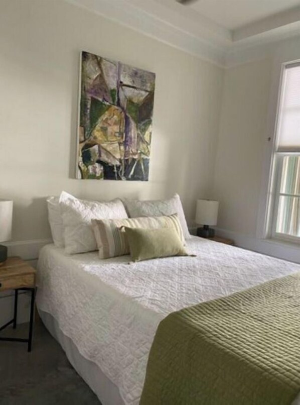 Une chambre à coucher avec un grand lit, une table de chevet et une fenêtre.