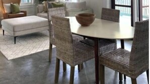 A dining area with wicker chairs, a round table, and a ceiling fan.