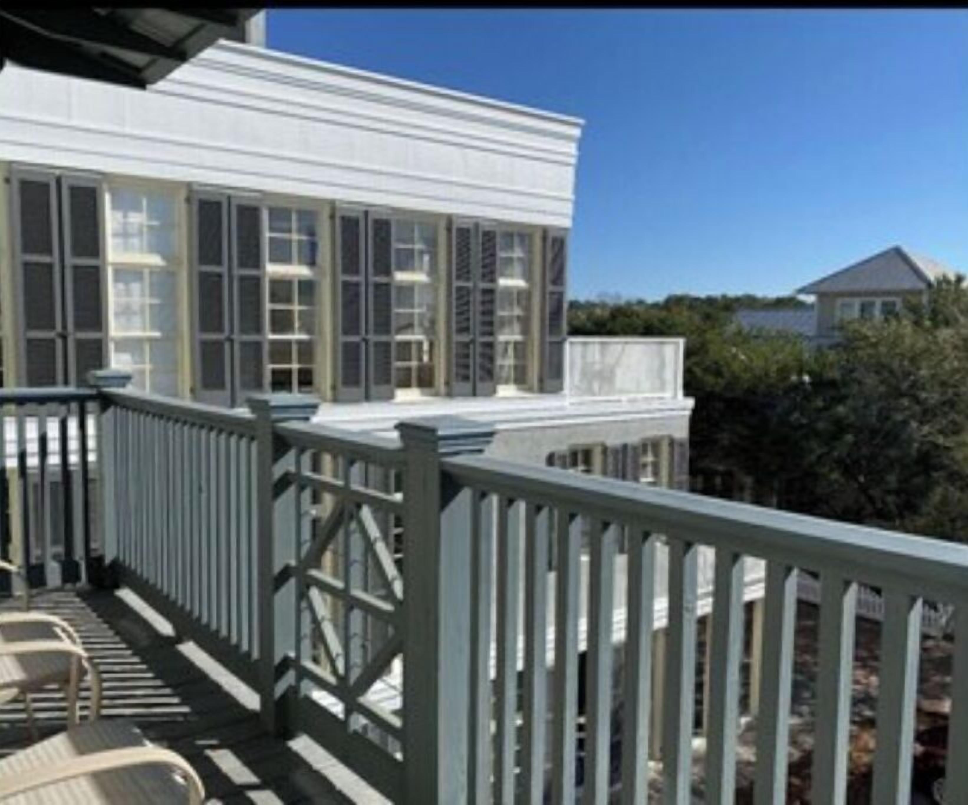 A coastal building with a balcony, large windows, and a white exterior.