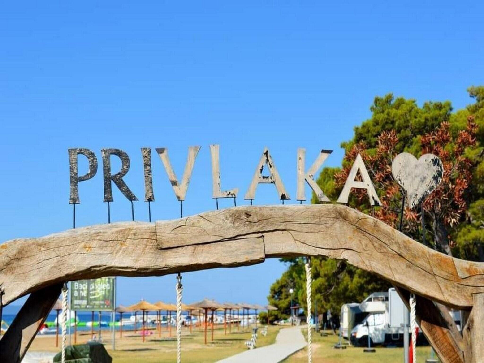 Une arche en bois sur laquelle sont inscrits les mots « PRIVLAKA » et un symbole en forme de cœur.