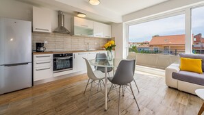 Eine moderne Küche mit Essbereich, großen Fenstern und einem Balkon mit einer Couch.
