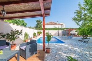 A poolside area with wicker furniture, potted plants, and a stone patio. - Modern two bedroom apartment with shared pool (Zadar)