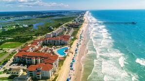 An aerial view of a coastal hotel with multiple buildings, a beach, and a pier extending into the ocean. - Elegant Beach Escape, Warm, Comfy Cozy, Family fun, Massage Chair, Retro Games (North Topsail Beach)