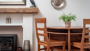 Uma mesa de jantar de madeira com cadeiras, uma planta em vaso, um prato decorativo e um quadro na parede.