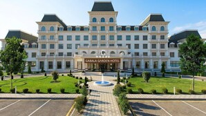 A large, multi-story hotel with a symmetrical facade, a central entrance, and a well-maintained lawn with a circular fountain. - Gabala Garden Hotel (Gabala)