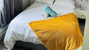 A bedroom with a bed, a nightstand, a lamp, and a window with curtains. - Lovely 2-bed House in Rochester (Rochester)