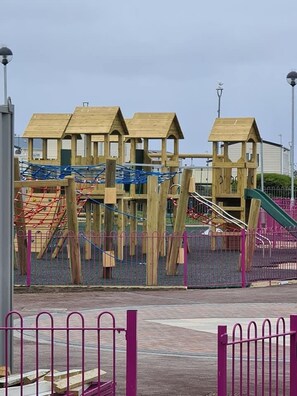 A playground with wooden climbing structures and a slide.