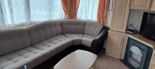 A living room with a curved sofa, a small table, a television, and a fireplace.