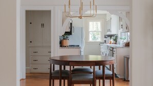 A modern kitchen with white cabinets, a wooden dining table, and a pendant light. - Stylish Family/Pet Friendly Cottage in Coveted Clark Park with Fenced In Yard  (Champaign)