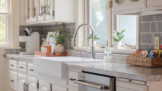 A kitchen with white cabinets, a stainless steel dishwasher, and a window with a view of greenery. - Stylish Family/Pet Friendly Cottage in Coveted Clark Park with Fenced In Yard  (Champaign)