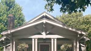 A two-story house with a front porch, a chimney, and a red door. - Stylish Family/Pet Friendly Cottage in Coveted Clark Park with Fenced In Yard  (Champaign)