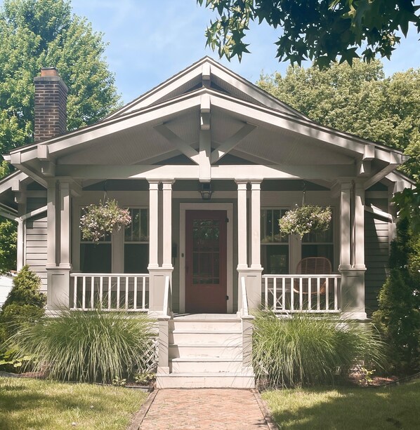A two-story house with a front porch, a chimney, and a red door.