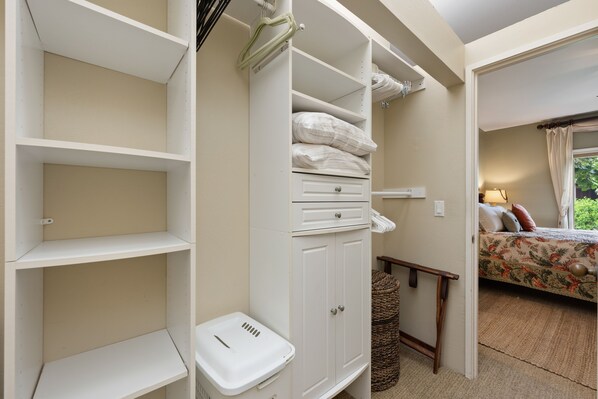 A bedroom with a bed, a nightstand, and a closet with shelves and a hanging rack.