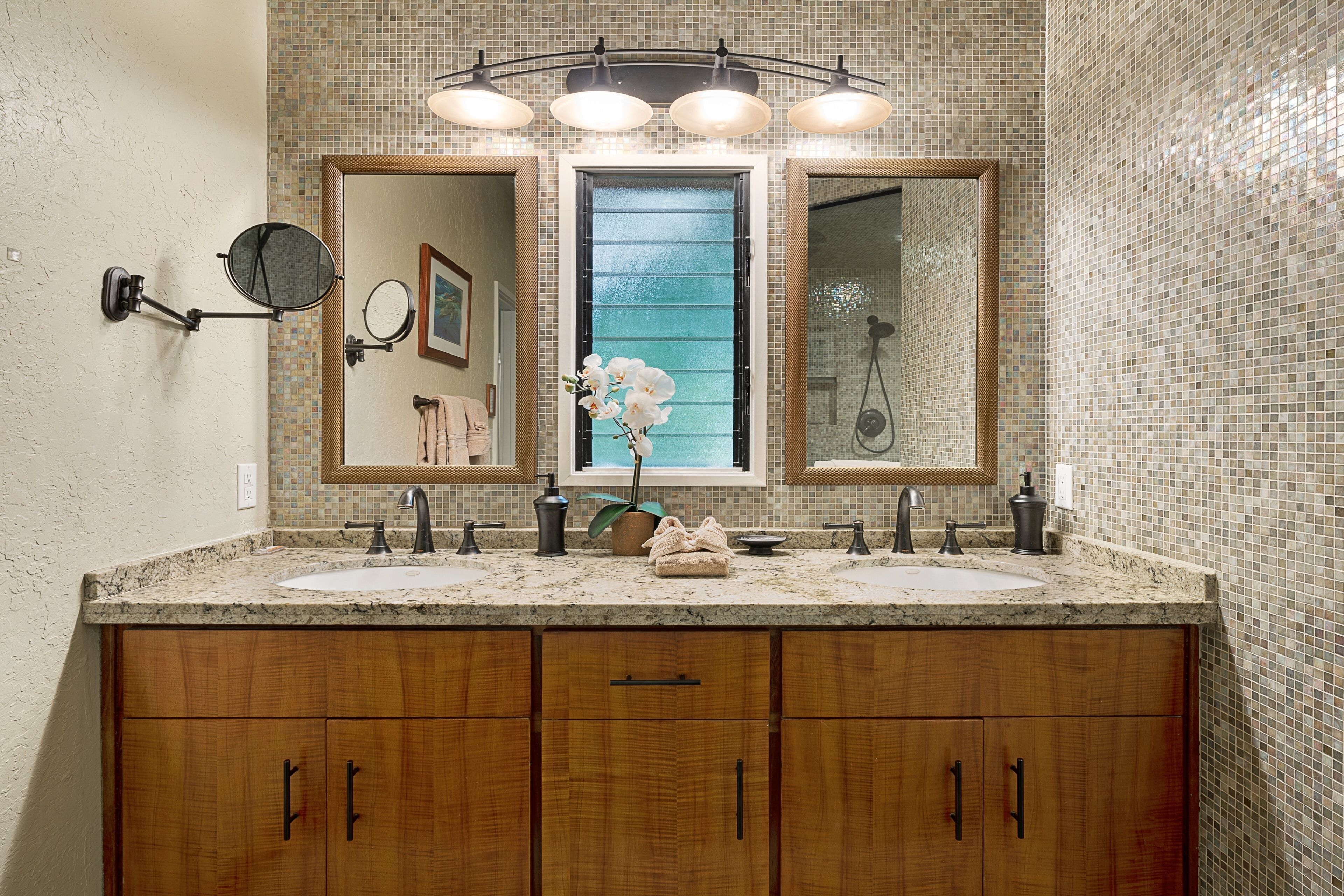 Un bagno con un ampio lavabo, due lavandini, uno specchio e una doccia.