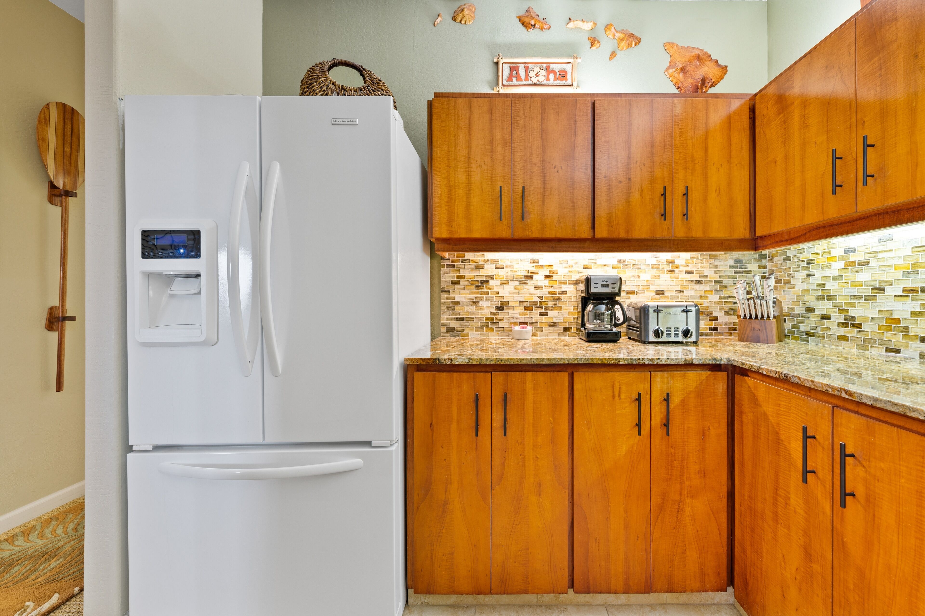 Une cuisine avec des meubles de rangement en bois, un réfrigérateur blanc, une machine à café et un four à micro-ondes.