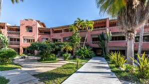 A hotel courtyard with a central walkway, surrounded by lush greenery and palm trees. - Condo 223 El Careyes Club & Residences (Costa Careyes)