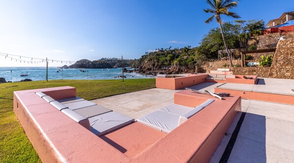 Un área de estar exterior moderna con vista al mar y un muro de piedra.