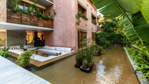 A modern building with a water feature, outdoor seating, and lush greenery. - Condo 223 El Careyes Club & Residences (Costa Careyes)