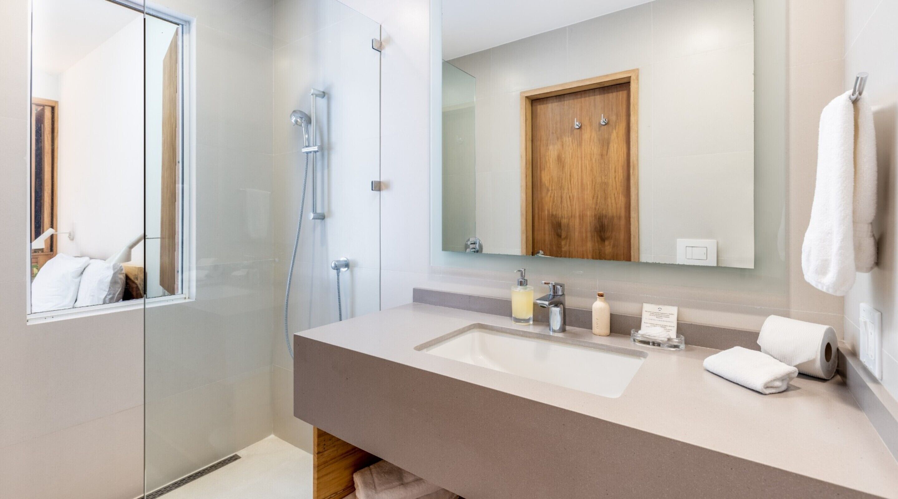 A modern bathroom with a large mirror, a wooden cabinet, and a shower.