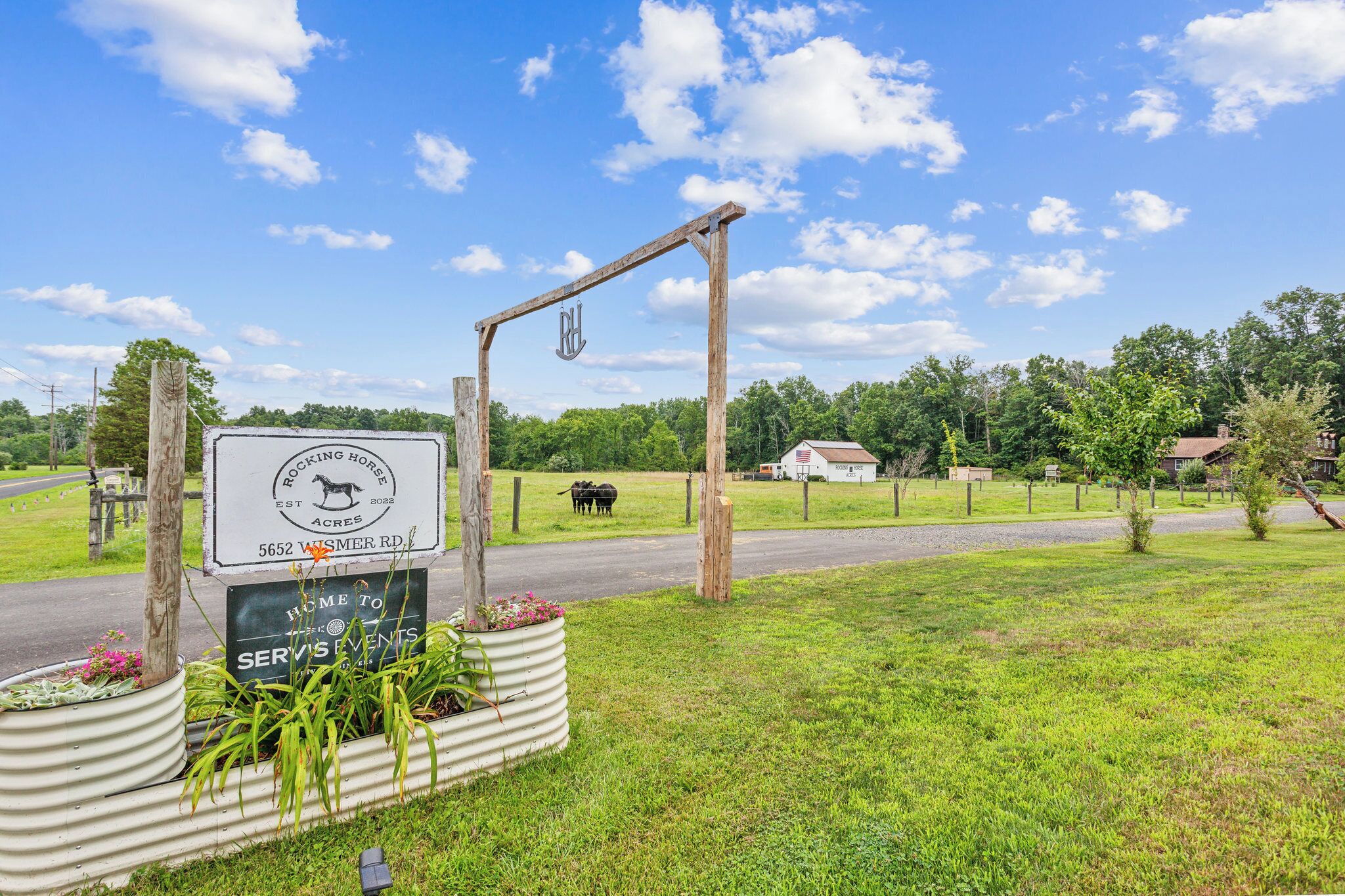 Un panneau indicateur rustique signalant un centre équestre, avec une arche en bois et un panneau d’affichage.