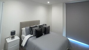 Une chambre à coucher moderne avec un lit, une table de chevet et une commode.