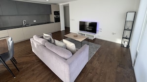 Un salon moderne avec un canapé gris, un téléviseur à écran plat et une table basse en bois.