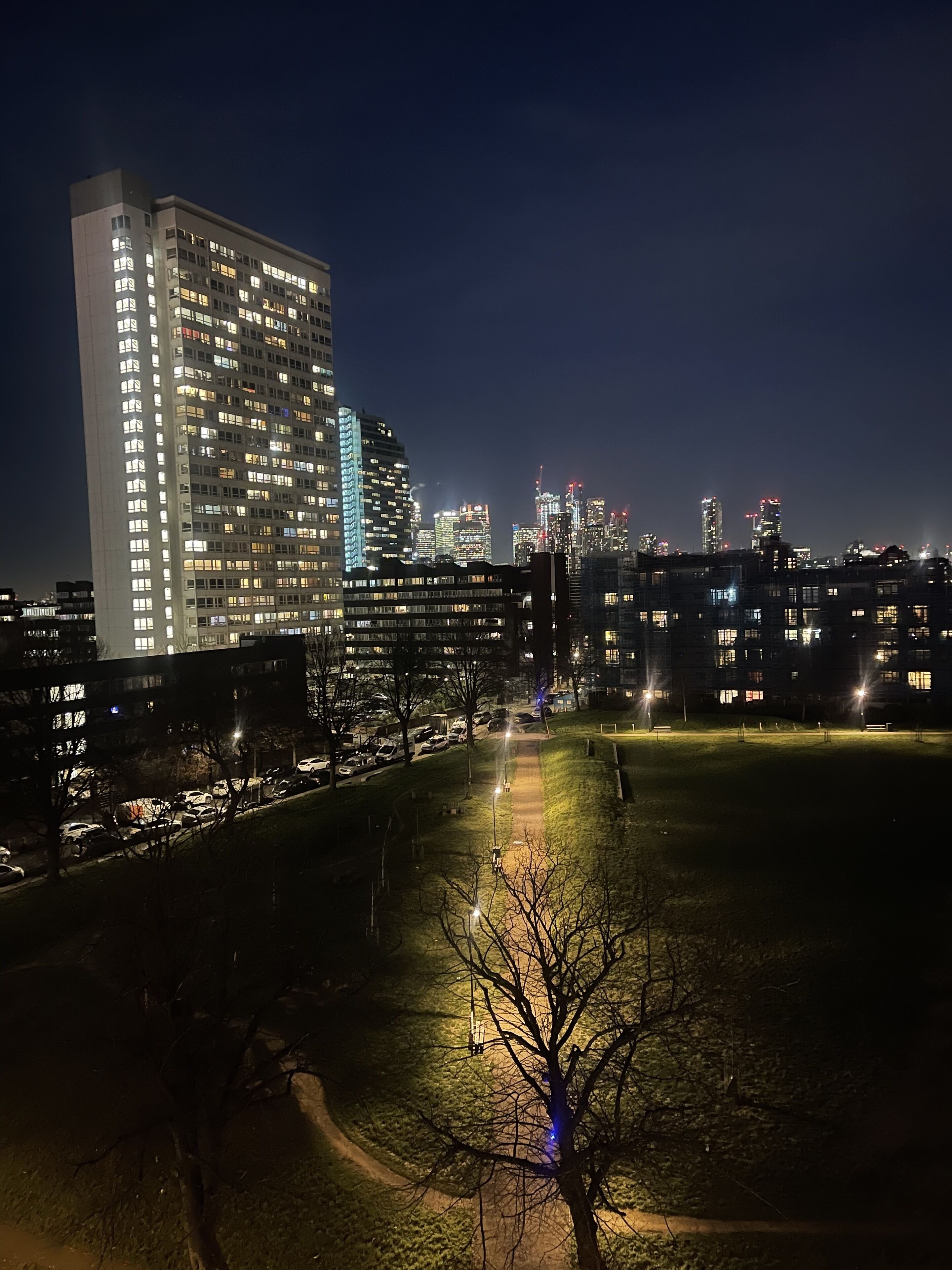 A nighttime cityscape with illuminated buildings and a park area.