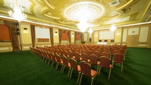 A conference room with rows of chairs, a stage with a podium, and a chandelier. - Qafqaz Resort (Gabala)