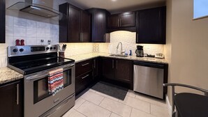 Una cocina moderna con armarios oscuros, electrodomésticos de acero inoxidable y un salpicadero de azulejos.
